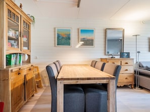 A dining area with a wooden table, chairs, a cabinet with glass doors, and two framed pictures on the wall. - Holiday Home in Bergen With Swimming Pool (Bergen)