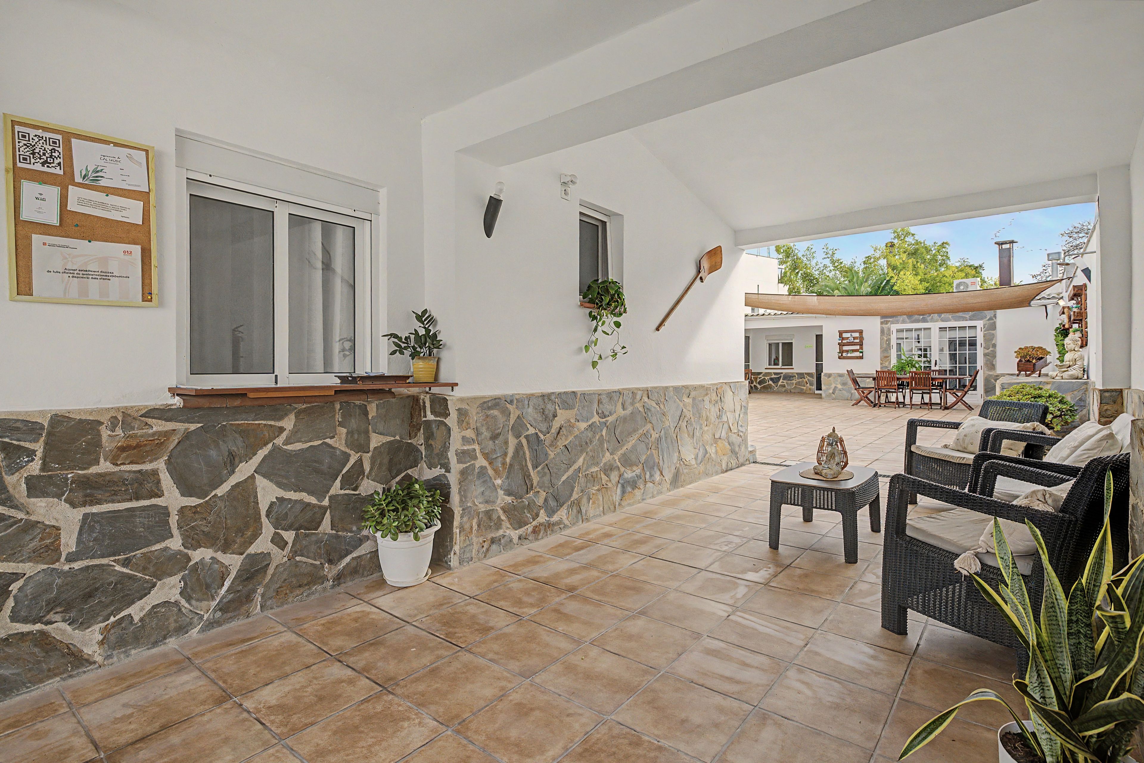 Un patio amplio con muros de piedra, mobiliario exterior y plantas en macetas.