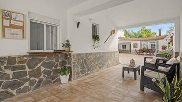 Un patio amplio con muros de piedra, mobiliario exterior y plantas en macetas.