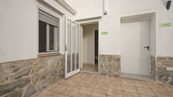 Un pasillo estrecho con una pared de piedra a un lado y una pared blanca al otro, que conduce a una puerta con un letrero que dice 'Mirador'.