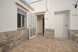 A narrow hallway with a stone wall on one side and a white wall on the other, leading to a door with a sign that reads 'Mirador.' - Room 'Mirador' with shared terrace, Wi-Fi and air conditioning (Poblenou del Delta)