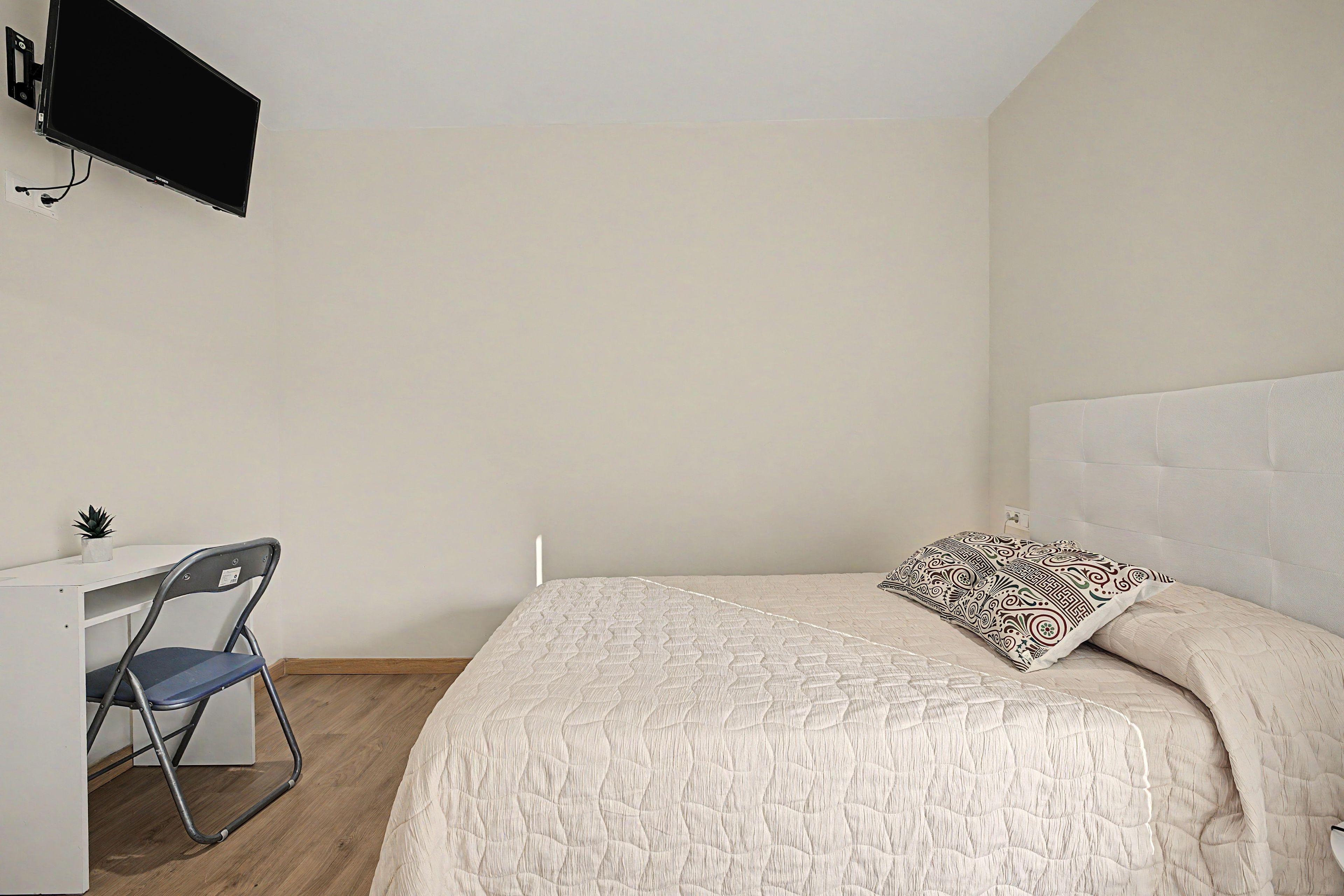 Un dormitorio con cama, escritorio y silla.