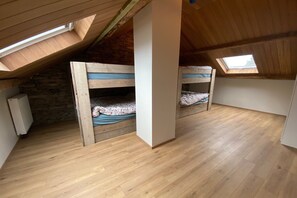 Ein Zimmer mit schrägem Dach, Holzbettställen und einem Oberlicht.