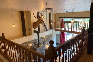 Ein mehrgeschossiges Interieur mit Kamin aus Stein, Holzbalkon und einer Hirschskulptur.