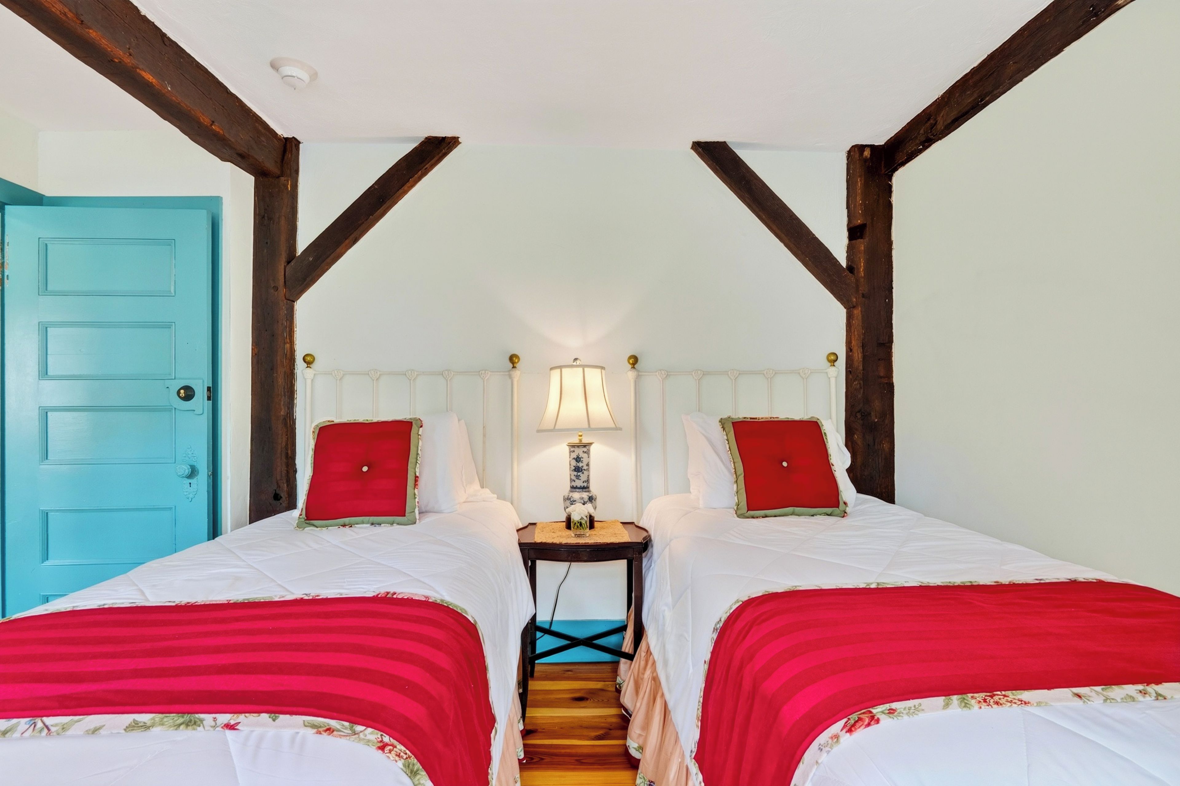 A room with two beds, a blue door, and a wooden staircase.