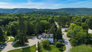 A large house surrounded by a forested area with a driveway leading to the entrance.