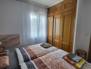 A bedroom with a bed, a wardrobe, a window with curtains, and a bedside table. - Holiday Home in Vinaros With Swimming Pool (Vinaros)