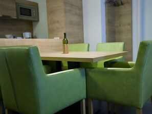 A dining area with a wooden table and green upholstered chairs. - H&P Residence Grafenmatt Type B (Feldberg)