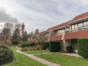 Ein Wohngebäude mit rotem Dach, einem Weg und einer Hecke.