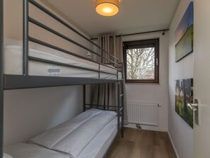 Ein Schlafraum mit Etagenbett, Fenster, Heizkörper und einem Bild an der Wand.