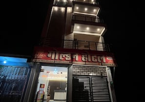 Un hotel con un letrero rojo, una entrada visible y un número de contacto.
