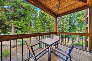 A wooden deck with a table and chairs, surrounded by trees. - Pine Views • Shared Pool + Spa | Steps to Northstar Shuttle | Northstar Pines (Truckee)
