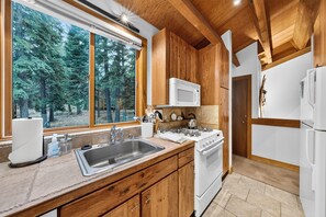 A kitchen with wooden cabinets, a stainless steel sink, a stove, and a microwave. - Pine Views • Shared Pool + Spa | Steps to Northstar Shuttle | Northstar Pines (Truckee)