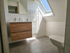 A modern bathroom with a skylight, a wooden vanity, and a toilet. - Holiday Home With 1 Bedroom (Aagtekerke)