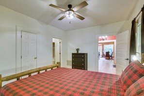 A bedroom with a bed, a dresser, a ceiling fan, and a door leading to another room. - Brevard Retreat w/ Hot Tub & Copper Soaking Tub (Brevard)
