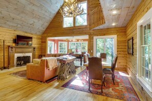 A spacious living room with a fireplace, a television, and a dining area with a table and chairs. - Brevard Retreat w/ Hot Tub & Copper Soaking Tub (Brevard)