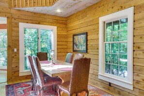 A wooden-paneled room with a dining table and chairs, large windows, and a framed picture on the wall. - Brevard Retreat w/ Hot Tub & Copper Soaking Tub (Brevard)