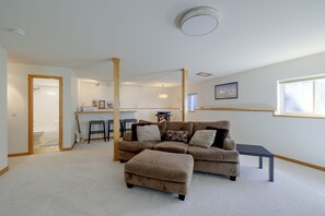A living room with a sofa, ottoman, and a small table. There is a kitchen area in the background with stools. - Private Sauna at Family-Friendly Eagle Home w/Deck (Eagle)