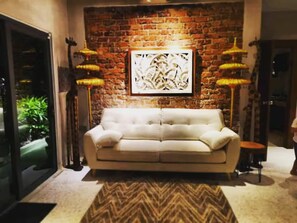 A living room with a brick wall, a white sofa, and two floor lamps.