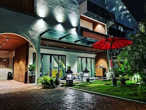 A modern building with a glass facade, a red umbrella, and a well-maintained garden.