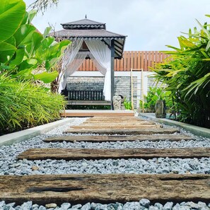 A pathway leading to a traditional-style building with a tiled roof and a wooden fence.