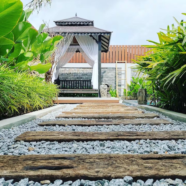 A pathway leading to a traditional-style building with a tiled roof and a wooden fence.