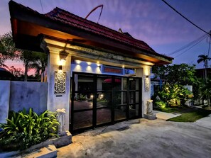 A building with a tiled roof, a glass entrance, and outdoor lighting.