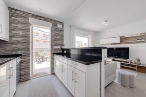 A modern kitchen with a black countertop, white cabinets, and a sliding glass door leading to an outdoor area. - CB Living - Ground floor apartment in Punta Prima (Torrevieja)