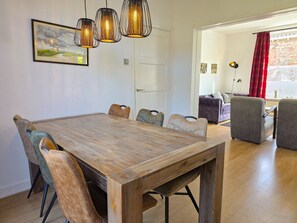 Ein Essbereich mit Holztisch und Stühlen, Pendelleuchten und einem Gemälde an der Wand.