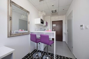 Et stilfuldt badeværelse med et stort spejl, et hvidt toiletbord og to lilla stole.