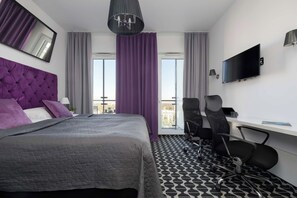 Ein modernes Hotelzimmer mit einem großen Bett, einem Schreibtisch, einem Stuhl, einem Fernseher und Blick auf die Stadt.