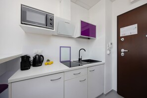 Eine moderne Küche mit Mikrowelle, Backofen und einem spiegel mit violettem Rahmen über der Spüle.