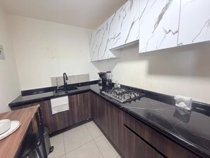 A kitchen with a black countertop, a stove, and a sink.