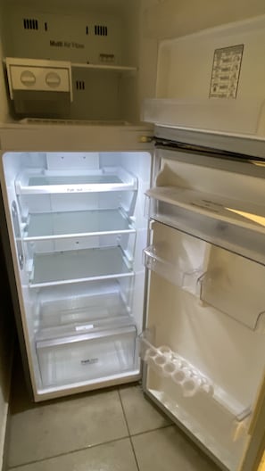 An open refrigerator with multiple shelves and drawers, including a fresh produce drawer.