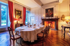 A formal dining room with a round table set for a meal, surrounded by wooden chairs.