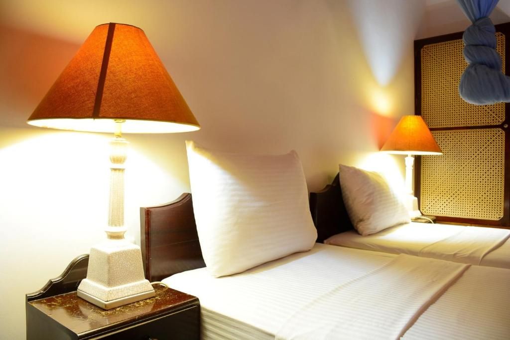 Una camera d'hotel con un letto, due abat-jour, un comodino e un pannello decorativo a parete.