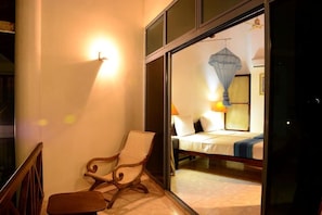 Una habitación con una cama, una silla y una ventana que da a otra habitación.