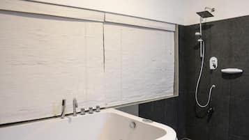 A modern bathroom with a freestanding bathtub, a showerhead, and a toilet.