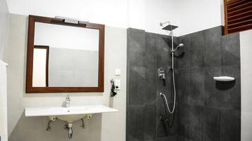 A bathroom with a white sink, a mirror, and a shower with a handheld showerhead.