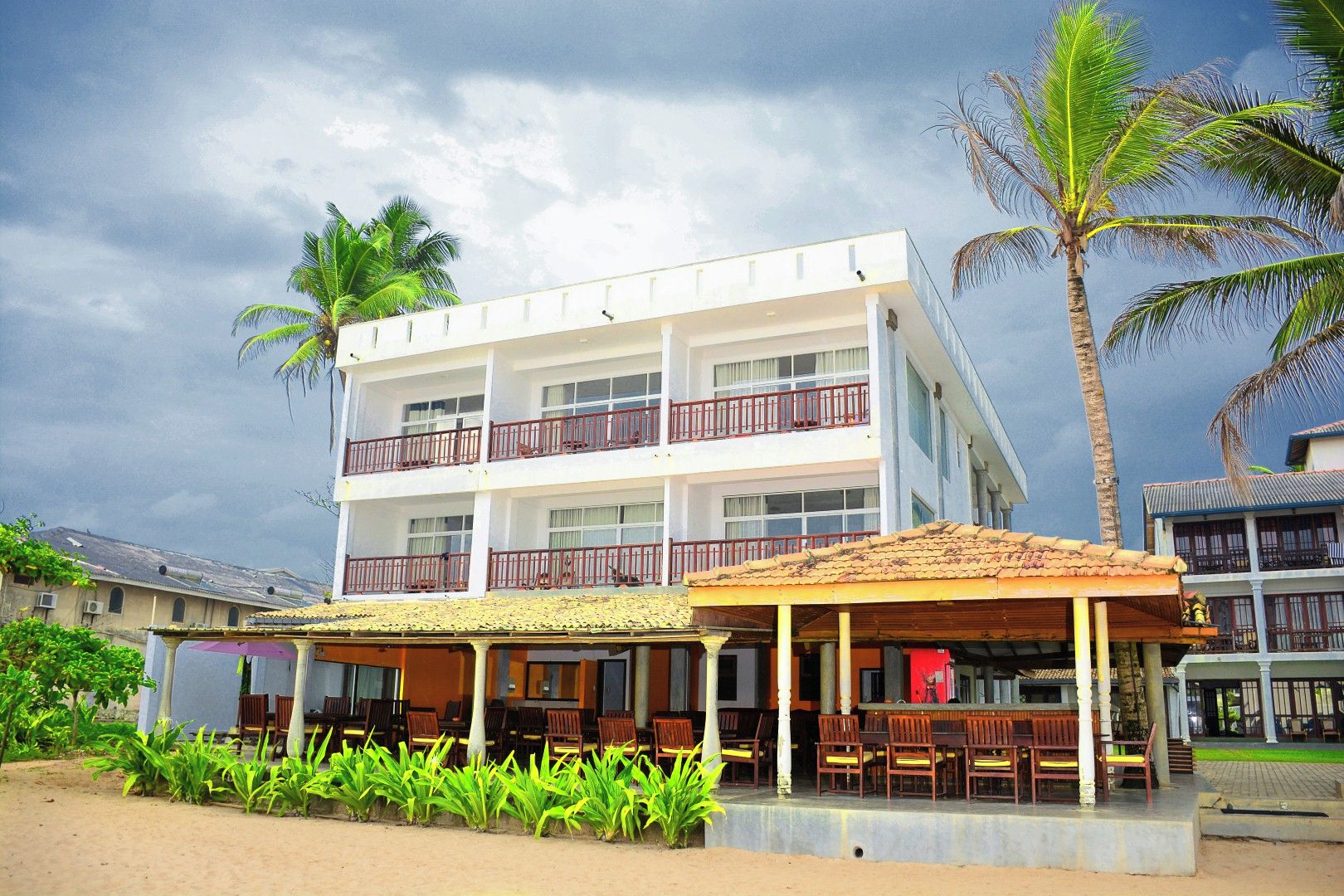 Un hotel de varios pisos con una zona de estar al aire libre techada y vista a la playa.