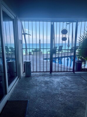 A balcony with a view of the beach and pool area, metal railings, and outdoor furniture. - Brisaazul Oceanfront 2BR (Puerto Vallarta)
