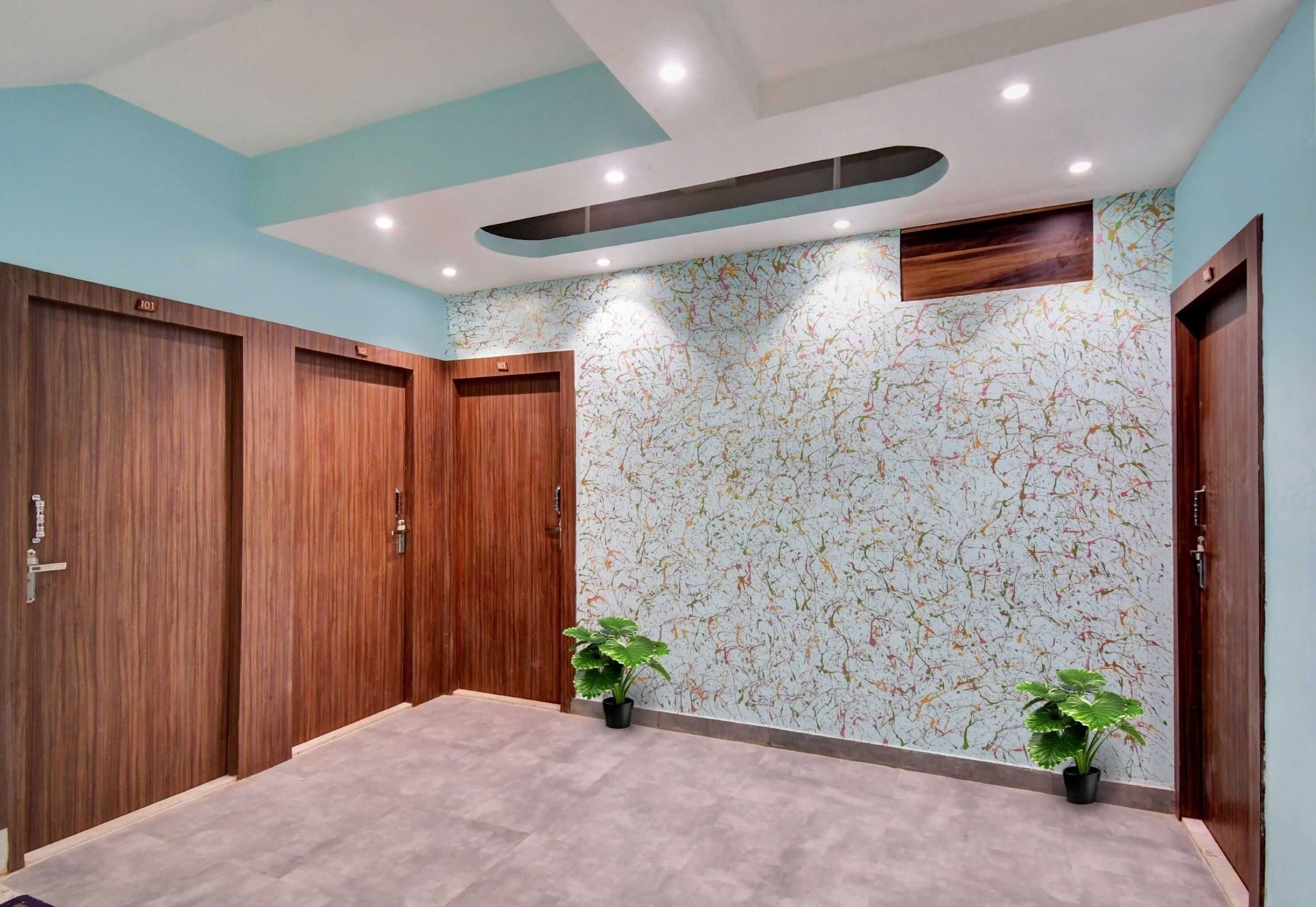 A room with wooden wardrobes, a patterned wall, and two potted plants.