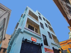 Un edificio de varios pisos con un cartel que dice 'OYO ROOMS', indicando un hotel o servicio de alojamiento.