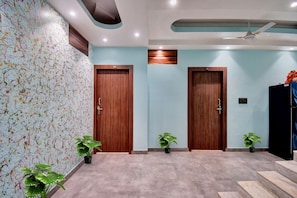 Un espace d’accueil avec deux portes en bois, un ventilateur de plafond et des plantes en pot.