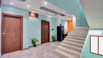 Un interior moderno con una escalera, puertas de madera y plantas en macetas.