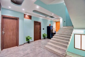 A modern interior with a staircase, wooden doors, and potted plants.
