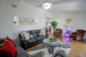 A modern living room with a leather sofa, a glass coffee table, and two armchairs. - Corporate Comfort & Luxury Extended Stay (Savannah)
