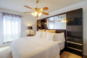 Ein Hotelzimmer mit Bett, Deckenventilator, Nachttisch und großem Spiegel.
