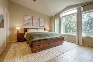A bedroom with a bed, bedside tables, a window with curtains, and wall art. - River Views & Gas Fire Table: Maiden Rock Retreat (Maiden Rock)