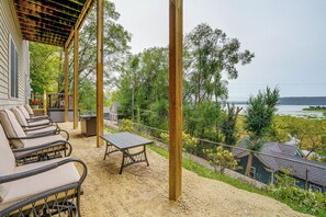 Un espacio de estar al aire libre cubierto con muebles de mimbre y una mesa, con vistas al agua y la vegetación.